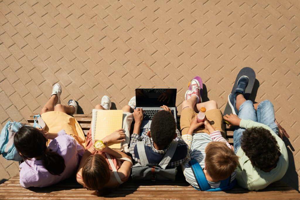 Aerial view of students studying on a bench with laptops and notebooks. A look at Education Systems Around the World 
